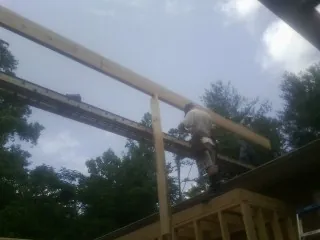 Carpenter setting a ridge beam over a new addition frame — Ice Dam Removal by Roofing Brothers in Medina