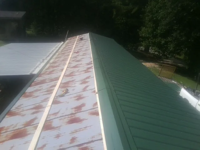 Old rusted panels beside newly installed green metal roofing — Wind Damage Roof Repair by Roofing Brothers in Medina
