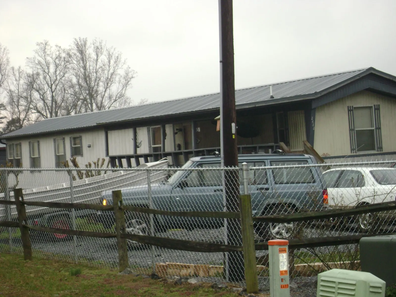 Dark metal roof on a long single story building behind a chain link fence in Medina